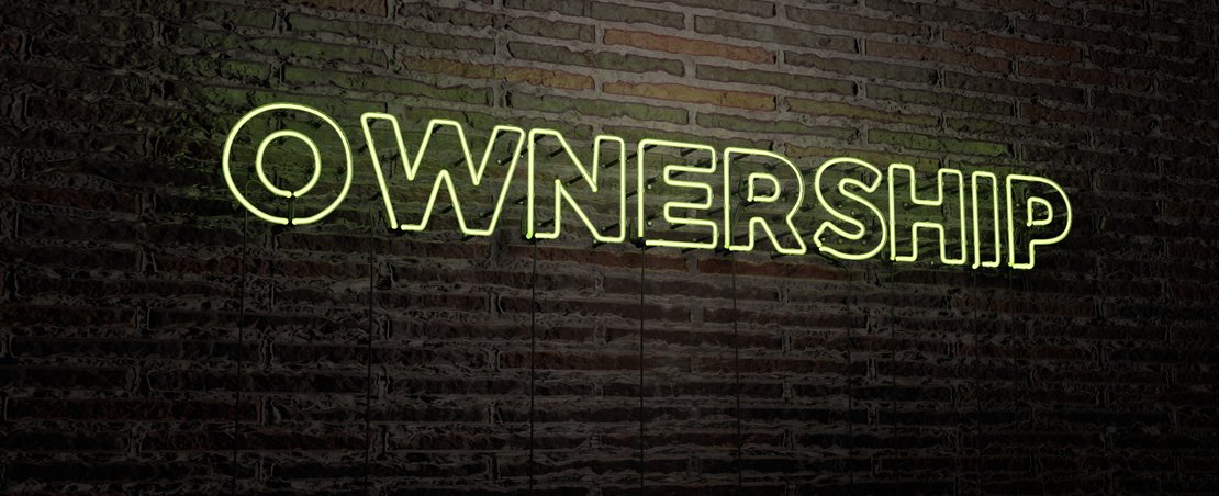 Neon sign saying OWNERSHIP - on brick wall