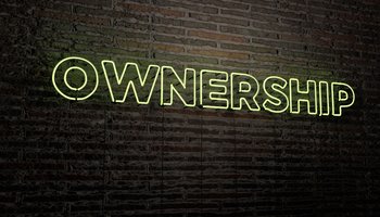 Neon sign saying OWNERSHIP - on brick wall