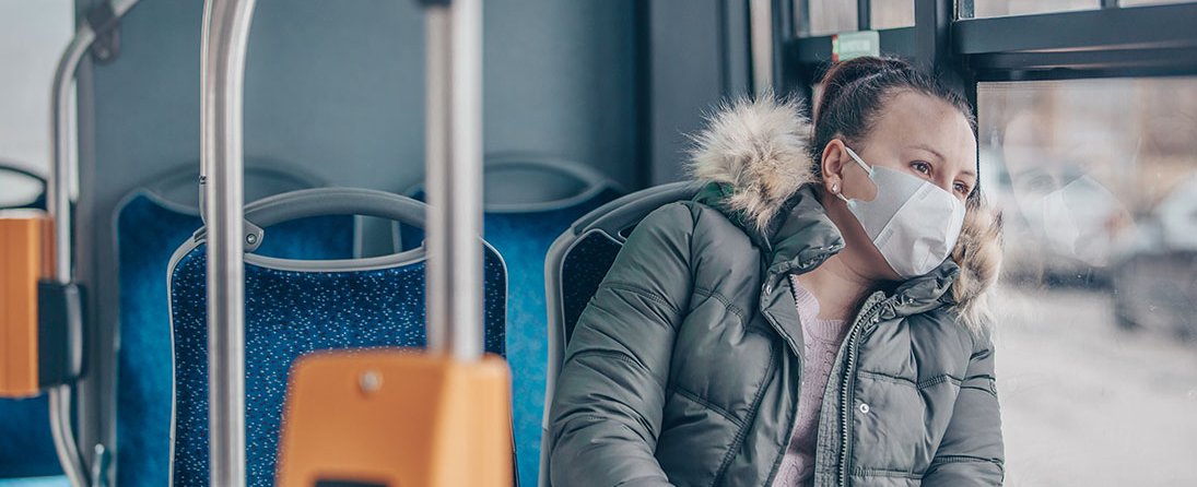 Coronavirus covid 2019 woman with respiratory mask traveling in the public transport by bus, transportation cocnept