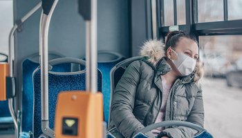 Coronavirus covid 2019 woman with respiratory mask traveling in the public transport by bus, transportation cocnept
