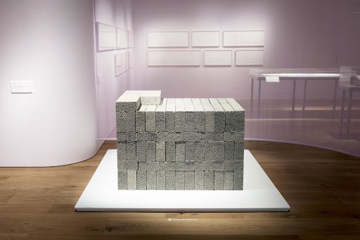 A Roomful of Air by David Rickard is a physical art piece that represents the unseen weight of air. The weight of air contained within a room is carefully measured and represented using concrete construction blocks resting on the floor.