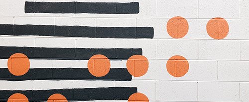 photo: orange dots over black stripes on white brick wall