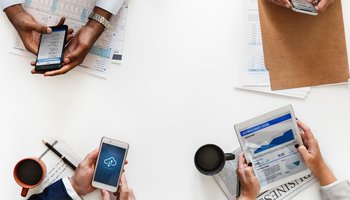 People holding devices and paper showing graphs and uploading - only hands/devices in shot