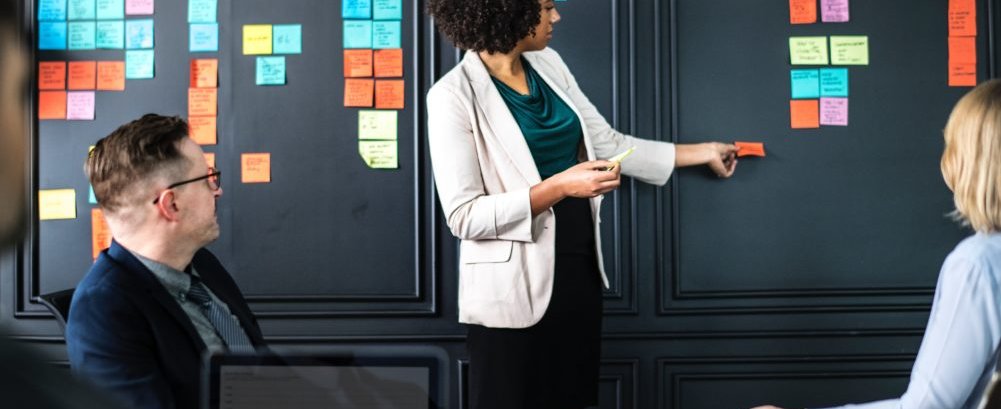 Woman placing sticky notes on wall in meeting