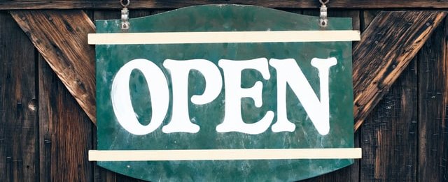 Green 'Open' sign attached to a wooden door