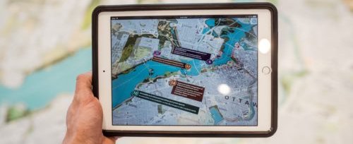 Person holding iPad with city plans over map